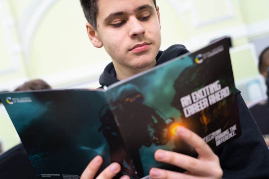 A student reads an RSC leaflet at the Top of the Bench final