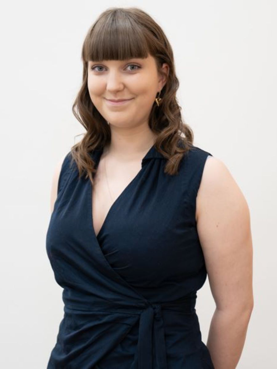 Mia Outram in a blue dress smiling for the camera