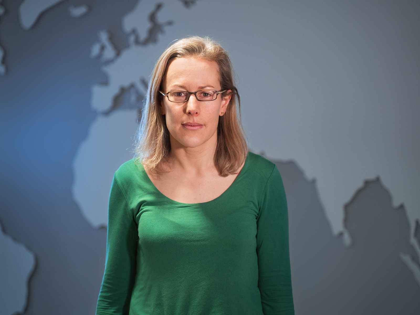A portrait of Tanya Sheridan standing in front of a map of part of the world