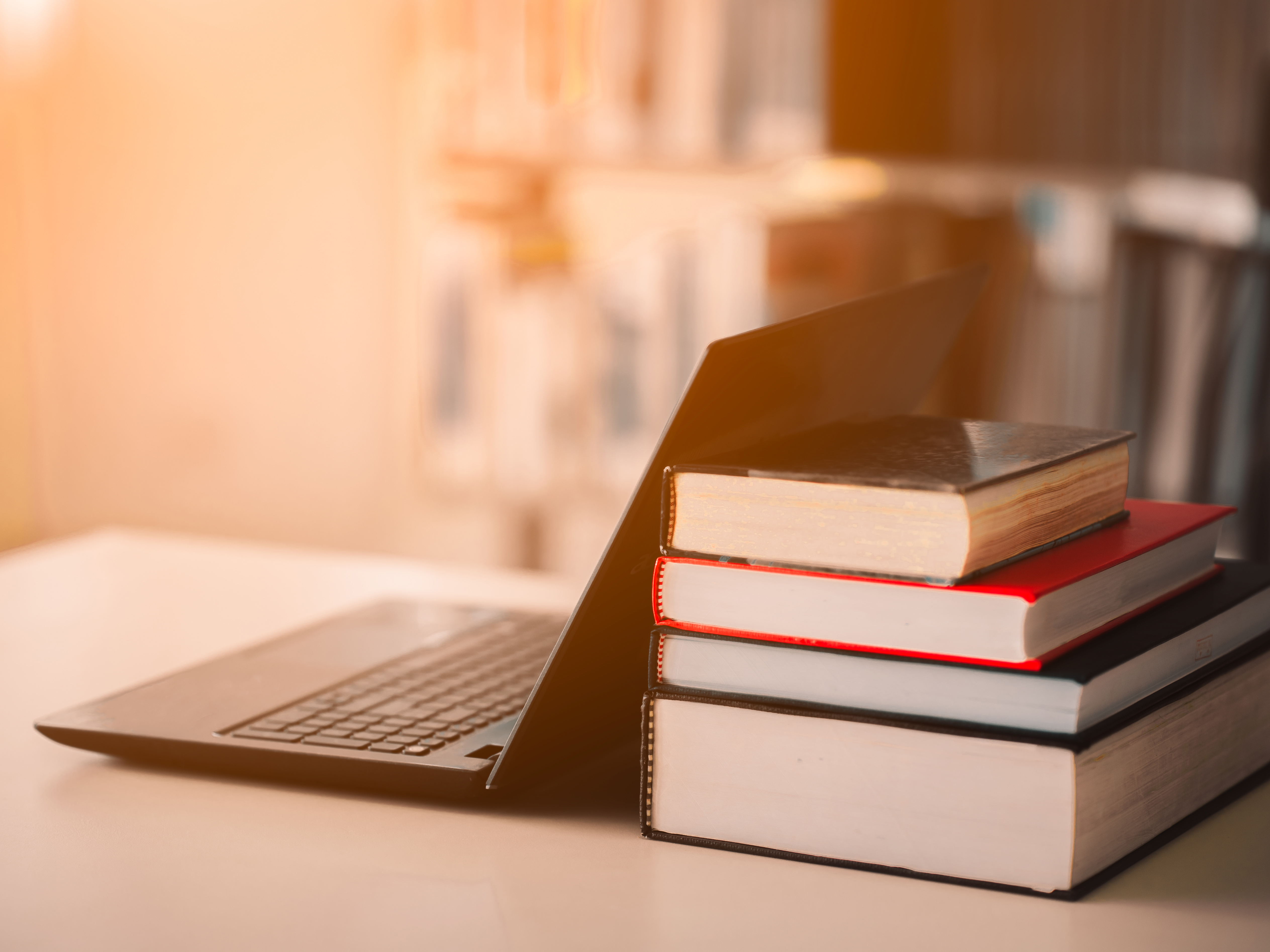 Stack of books with laptop on the side on wooden table 