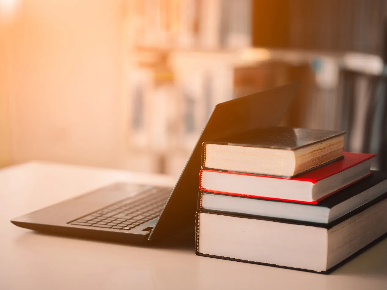 Stack of books with laptop on the side on wooden table