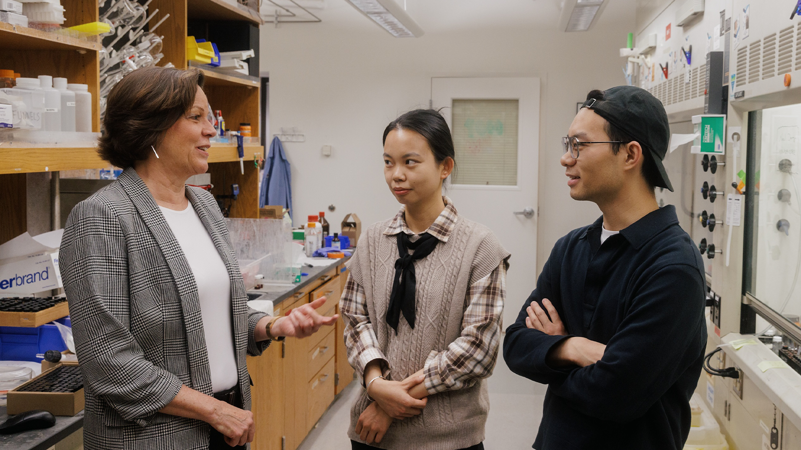 Professor Donna Blackmond in suit jacket with colleagues in the lab