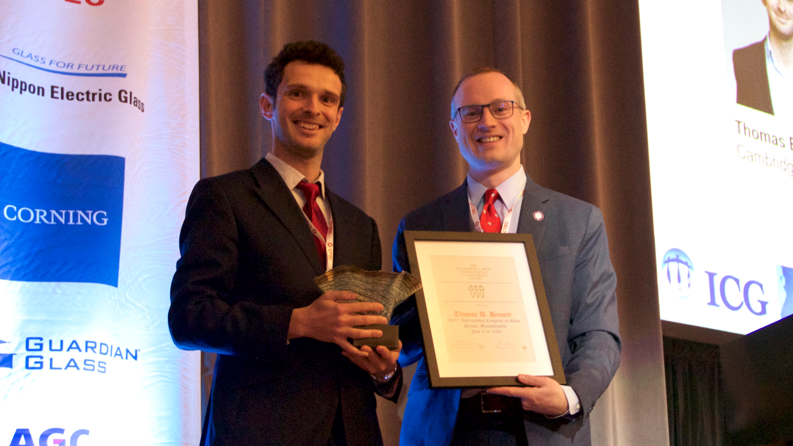 Pioneers in Hybrid Glass Research members holding a plaque and a trophy on a podium