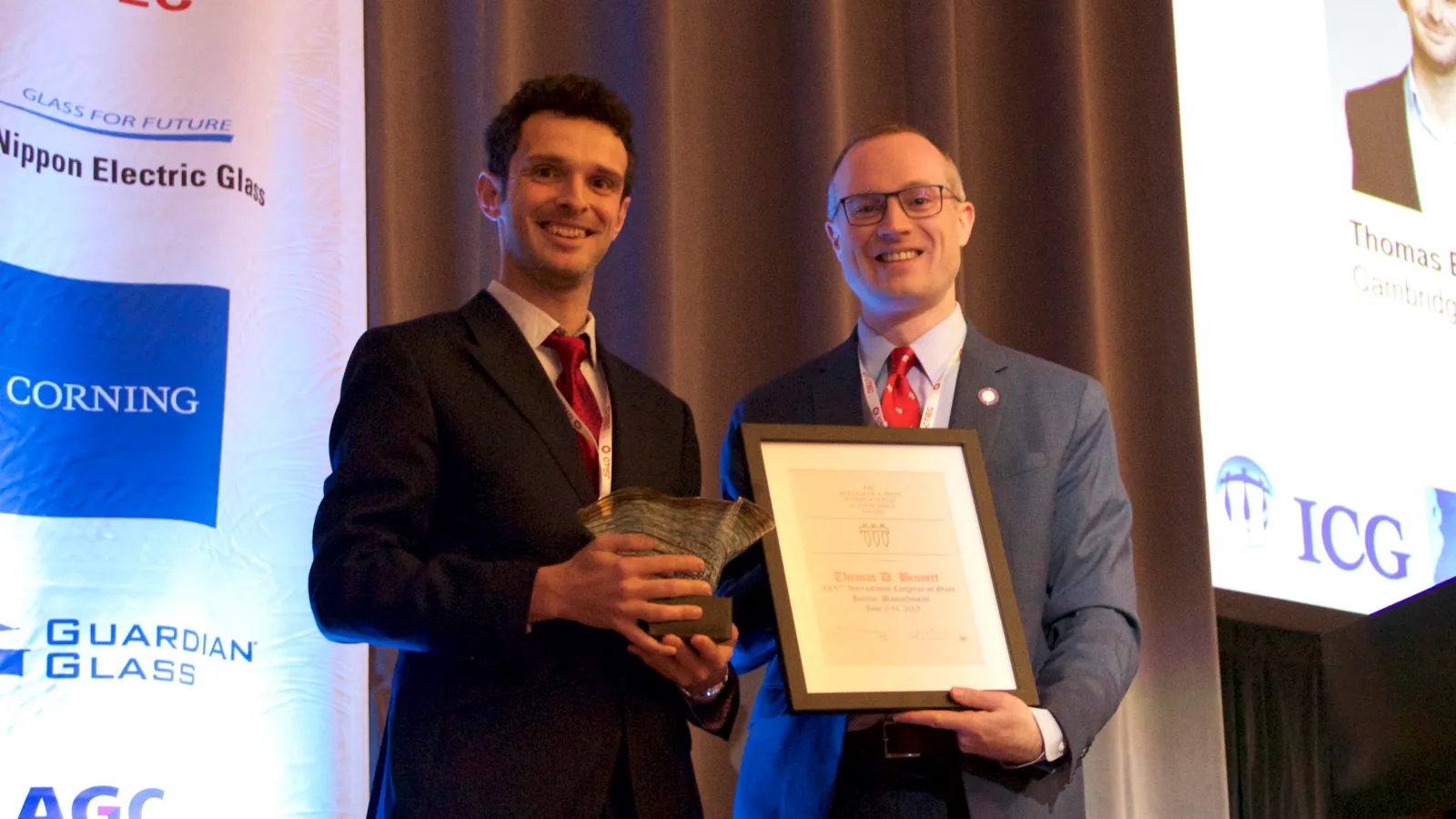 Pioneers in Hybrid Glass Research members holding a plaque and a trophy on a podium
