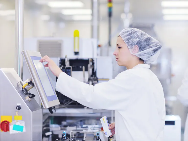 A female lab technician wearing a white coat working in lab