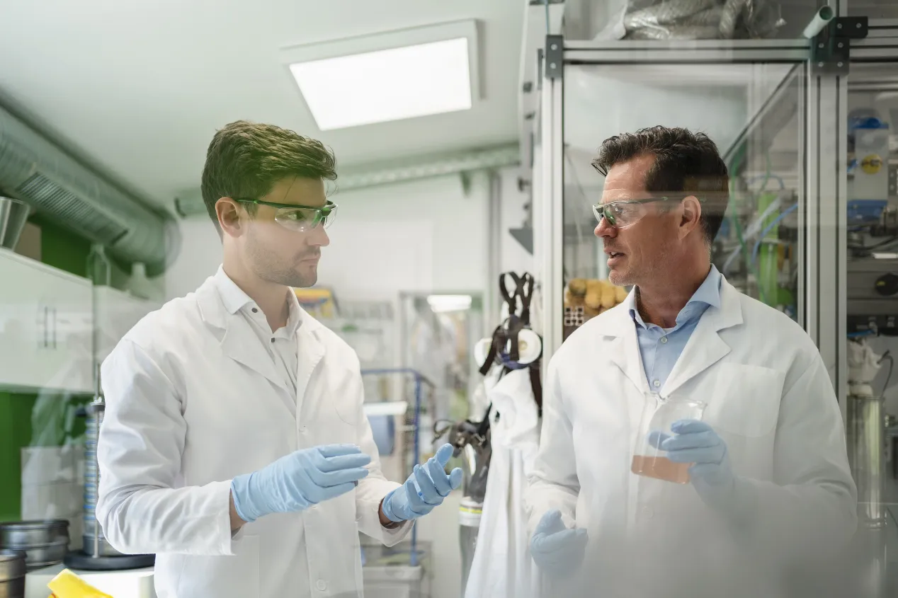 Scientists discussing with-colleague and doing thermolysis experiment in laboratory