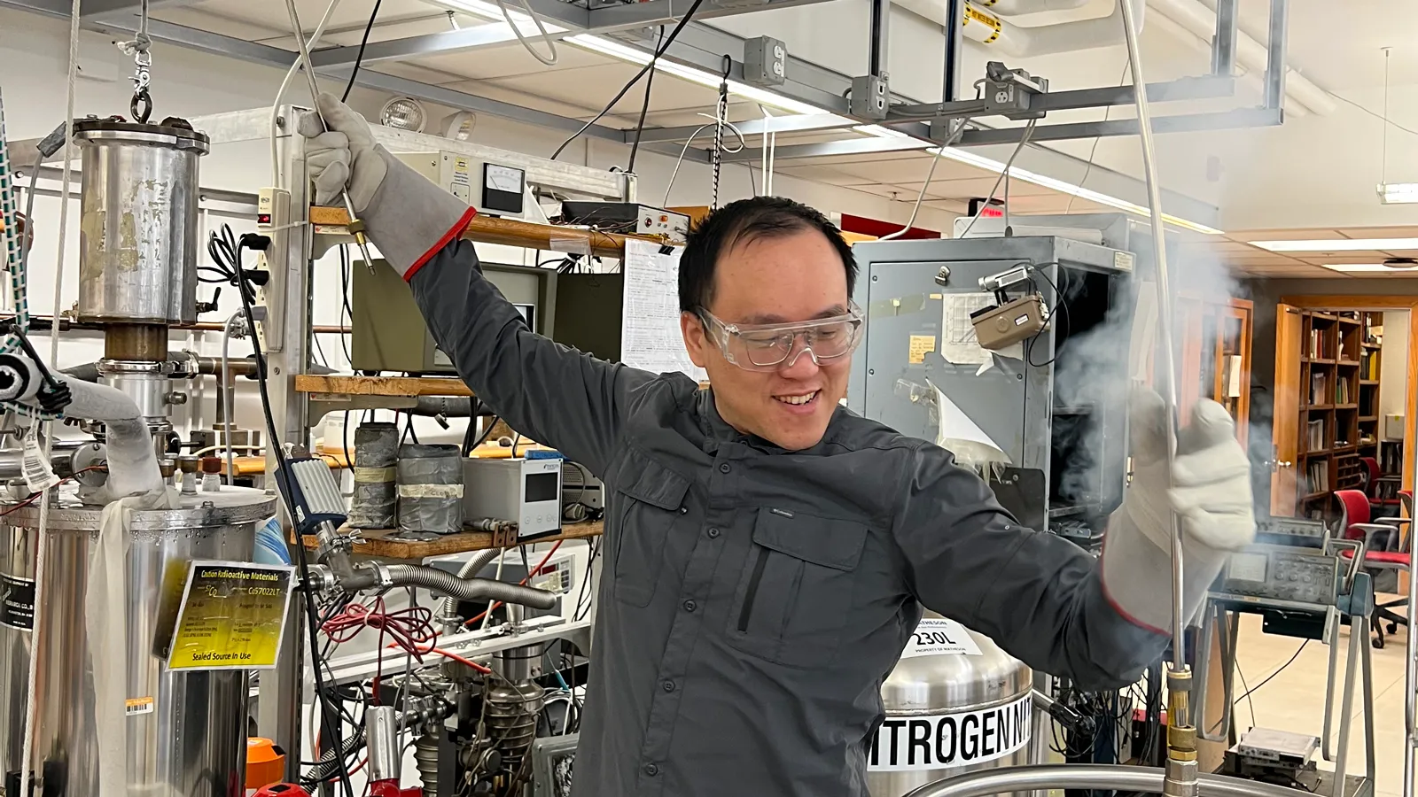 Nonheme iron-oxo oxidants team member wearing safety goggles and standing in a lab conducting an experiment that is giving of white vapour