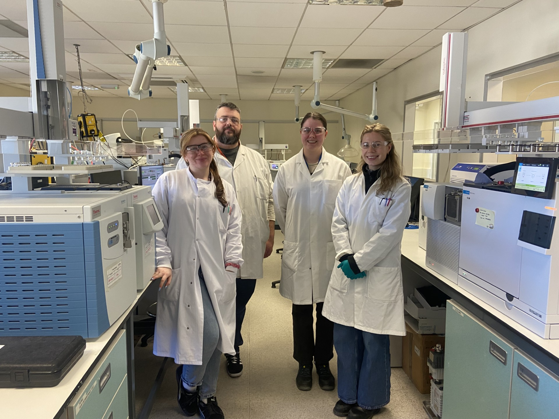 Four members of the Scottish Water team stand in white lab coats and goggles in their laboratory Four members of the Scottish Water team stand in white lab coats and goggles in their laboratory