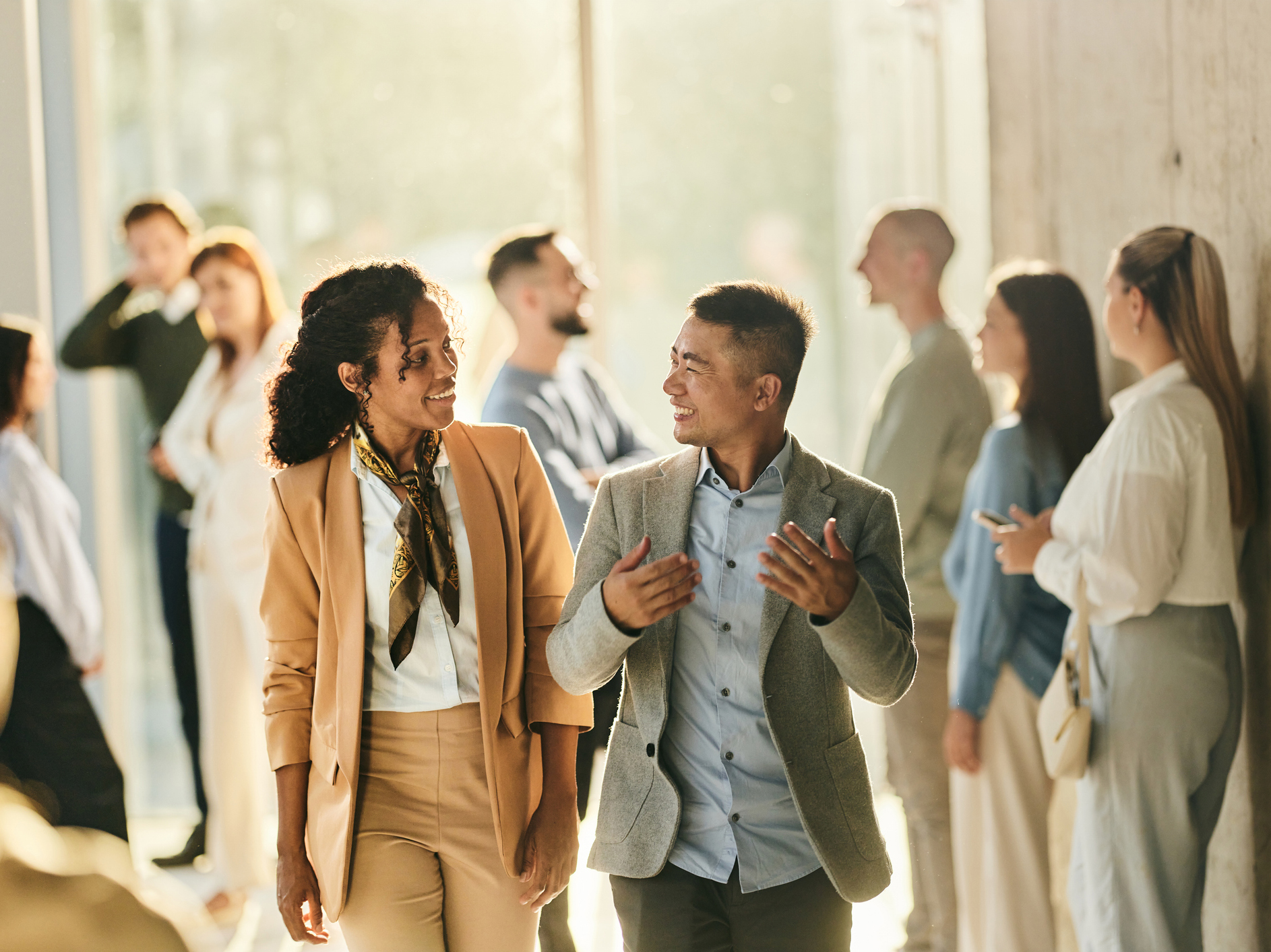 colleagues talking while walking through a busy hallway