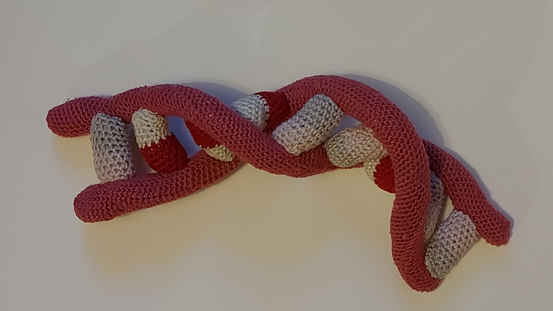 a knitted chain of DNA in red and grey