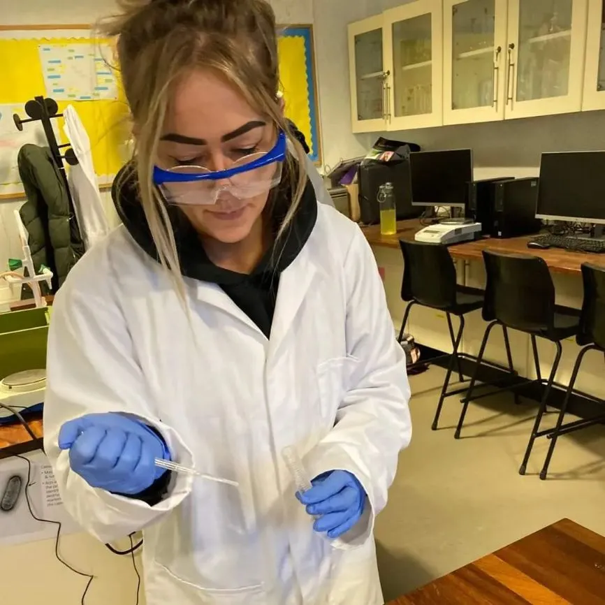 A girl puts some liquid into a test tube