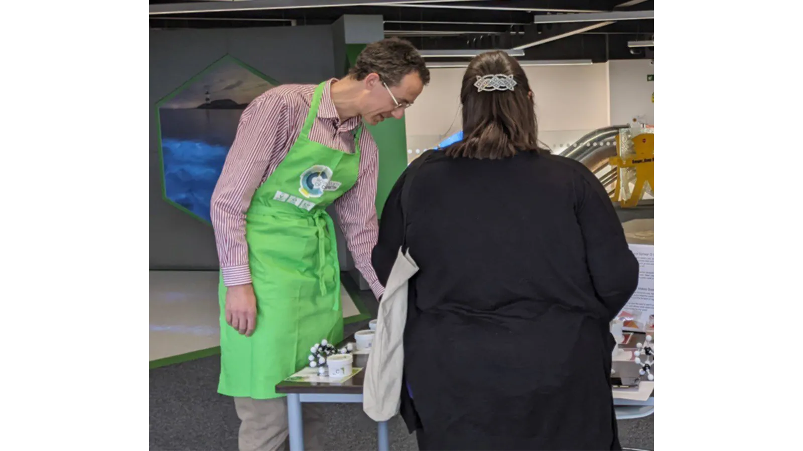 Dr James Redman with green apron with RSC logo on it, demonstrating with equipment