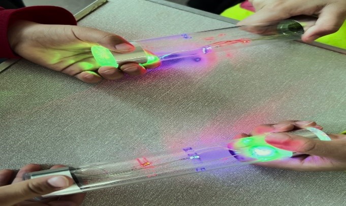Two pairs of hands on a glass tube with lights at each end