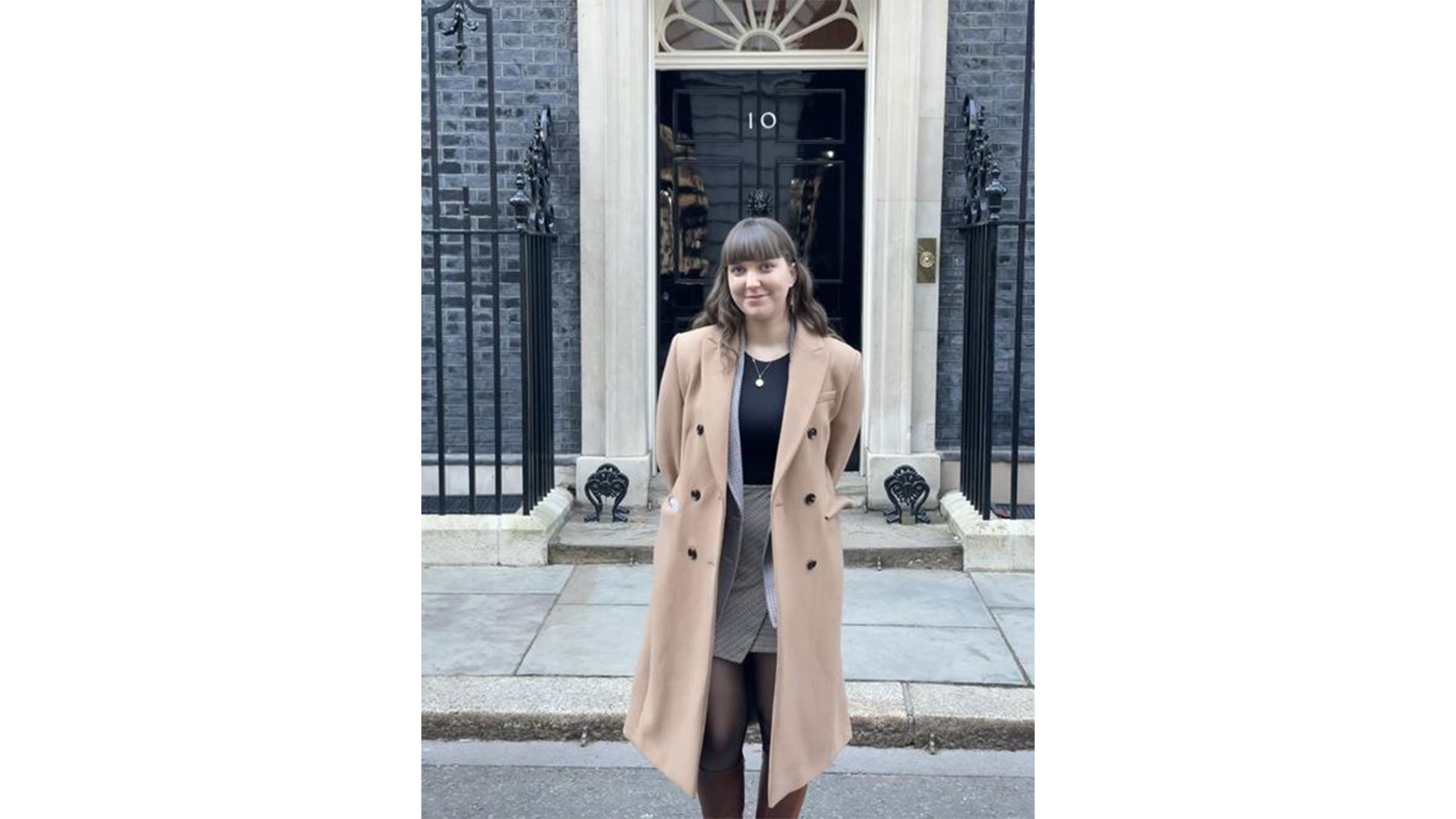 Mia Outram in a smart outfit standing in front of 10 Downing Street, London