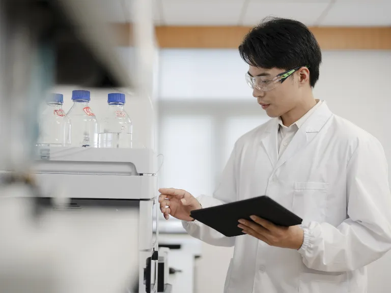 A science lab technician wearing white lab coat and glasses