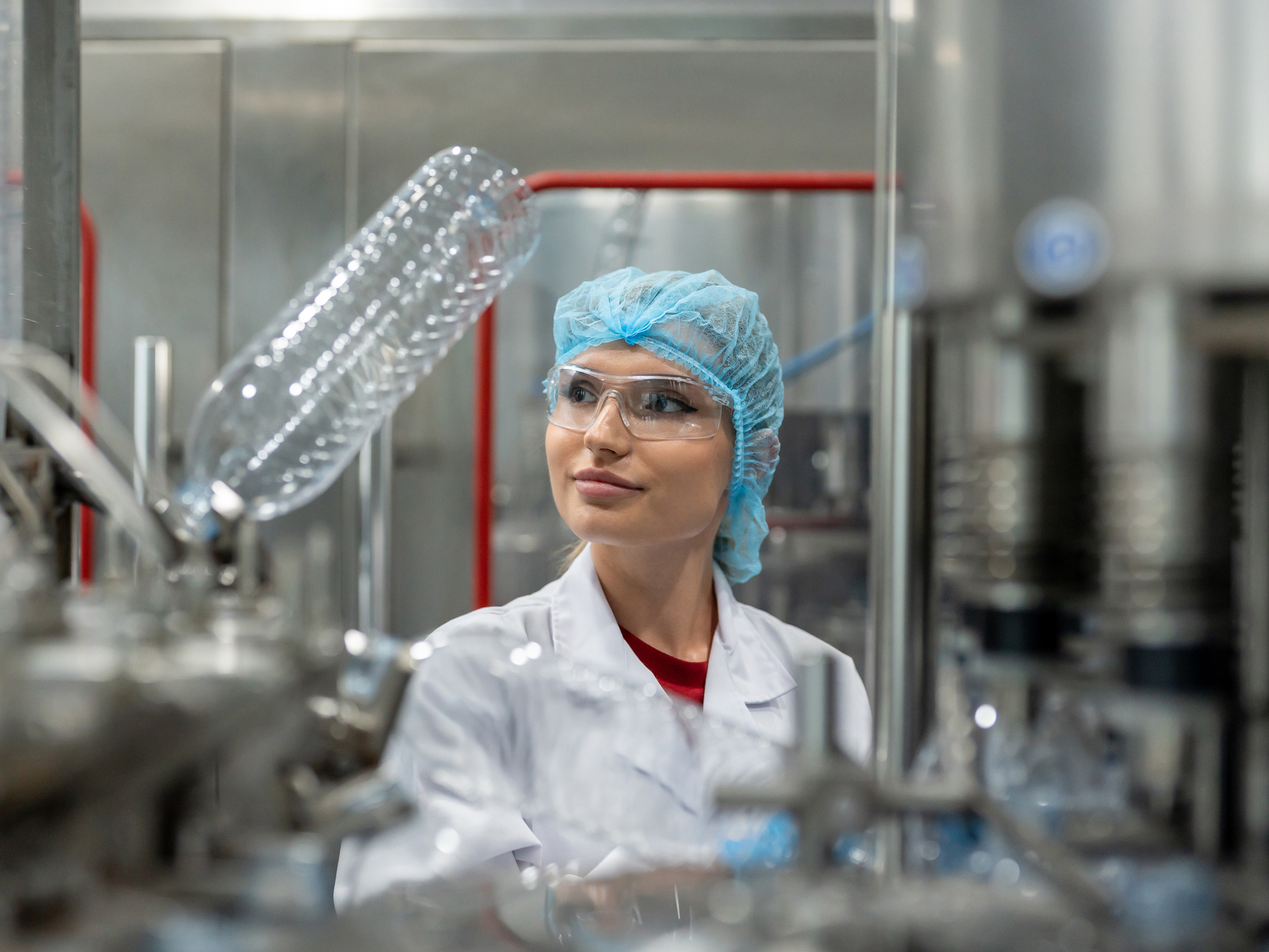 A female lab technician wearing white coat and blue hairnet in a lab