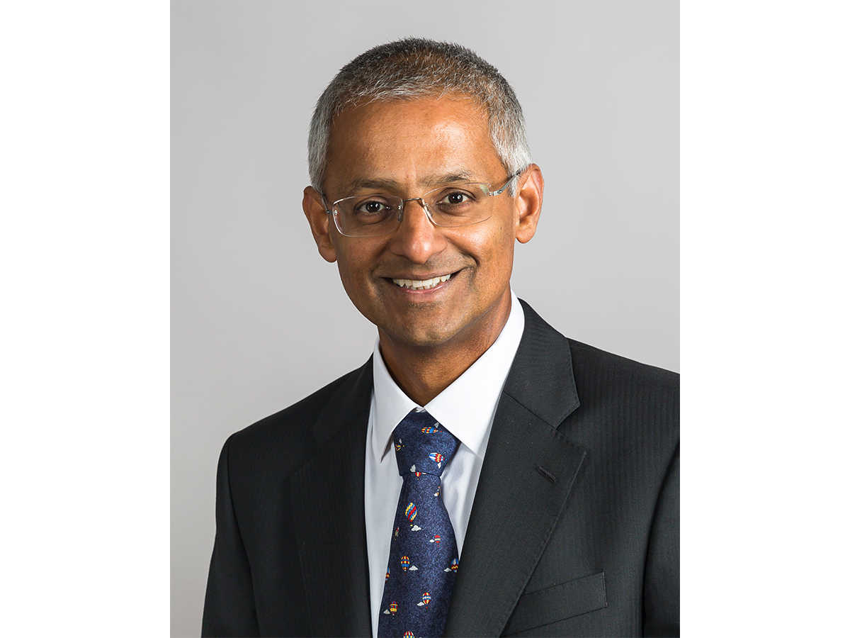 Professor Sir Shankar Balasubramanian smiling with glasses,suit and tie