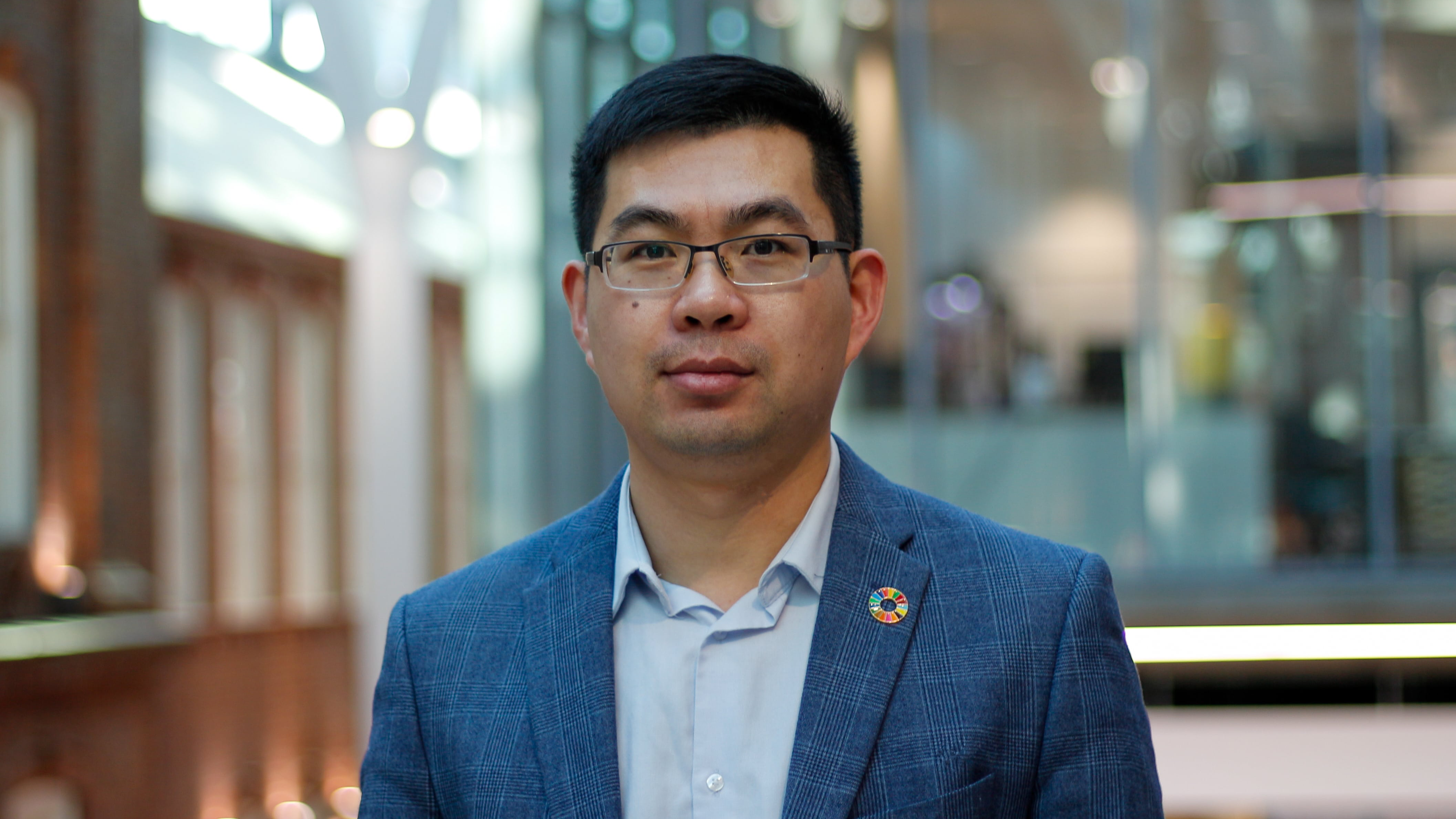 Dr Fanran Meng wearing glasses and a blue suit, posing outside for the camera