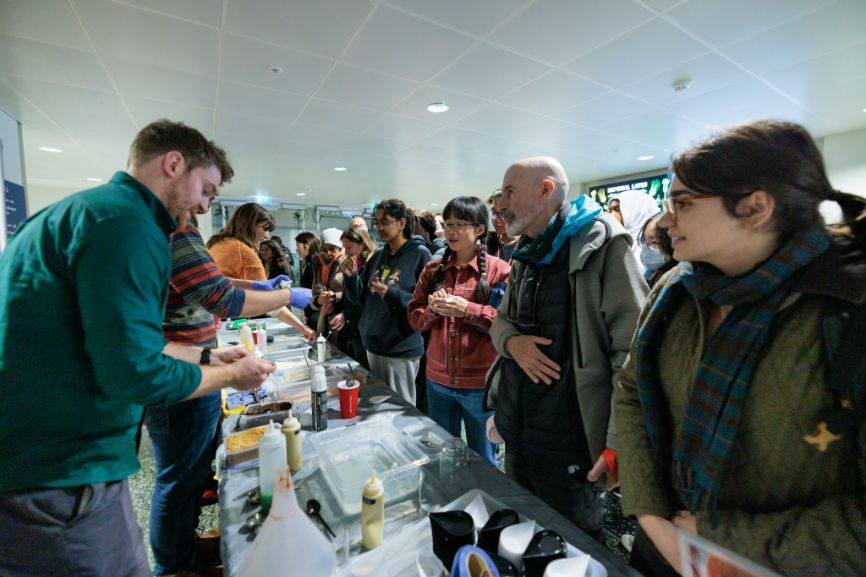 A man speaks with visitors to the Bitesized Soft Matter stand at the Imperial Lates event