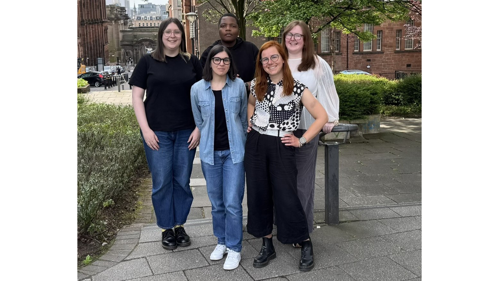 Dr Rebecca Beveridge with team members standing on outside steps smiling to camera