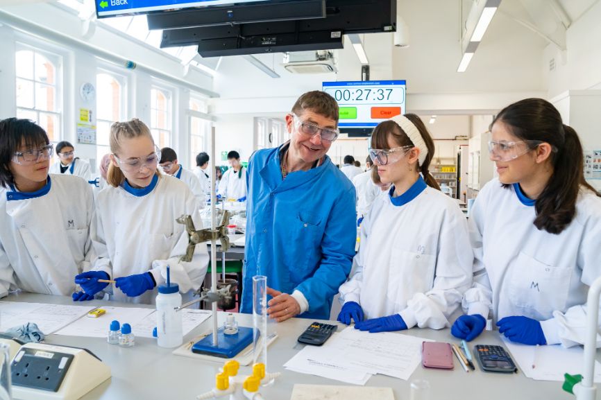 Dr Tony Raynham, UEL BSc chemistry course leader, stands in the middle of a group of four students conducting an experiment