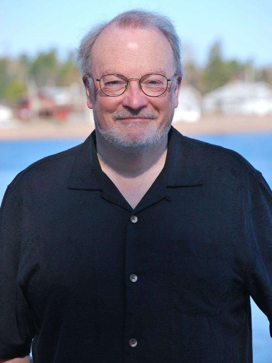 Professor James McCusker wearing glasses and a black shirt smiling for the camera