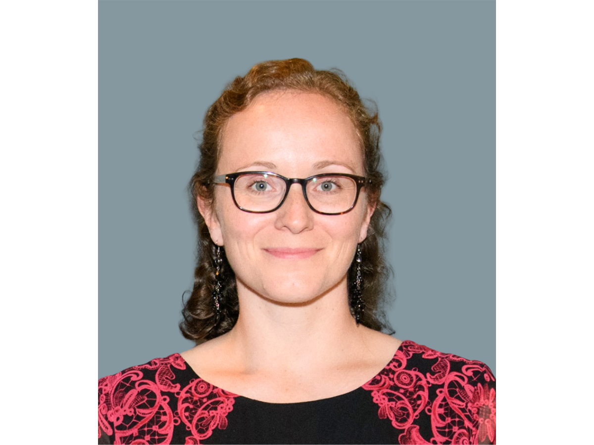 Professor Kim Jelfs wearing glasses and a red and black shirt, smiling for the camera