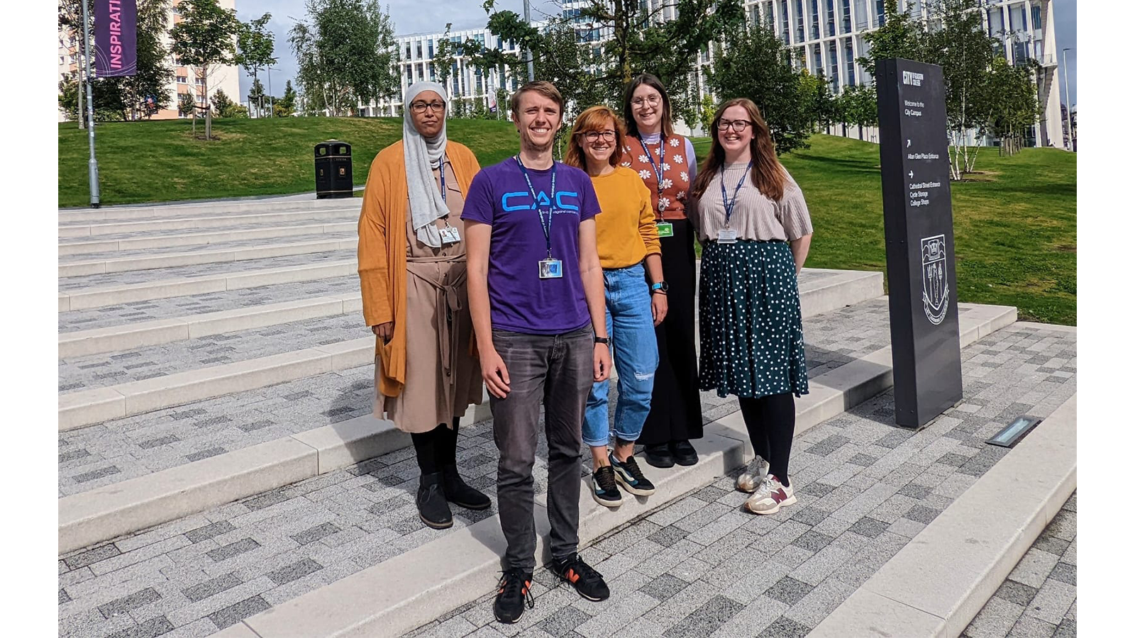 Dr Rebecca Beveridge with team members standing on outside steps smiling to camera