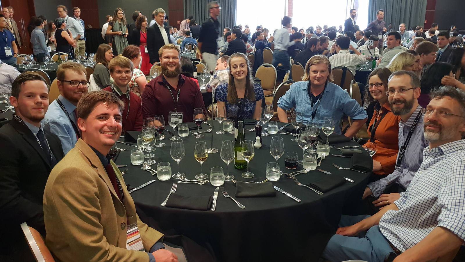 Members of the Pioneers in Hybrid Glass Research team sitting around a table with wine glasses at an event