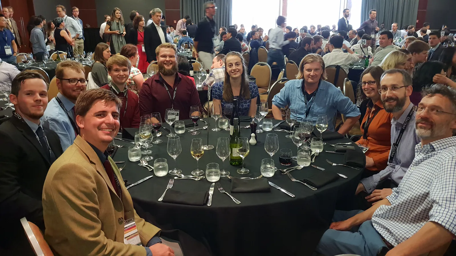 Members of the Pioneers in Hybrid Glass Research team sitting around a table with wine glasses at an event