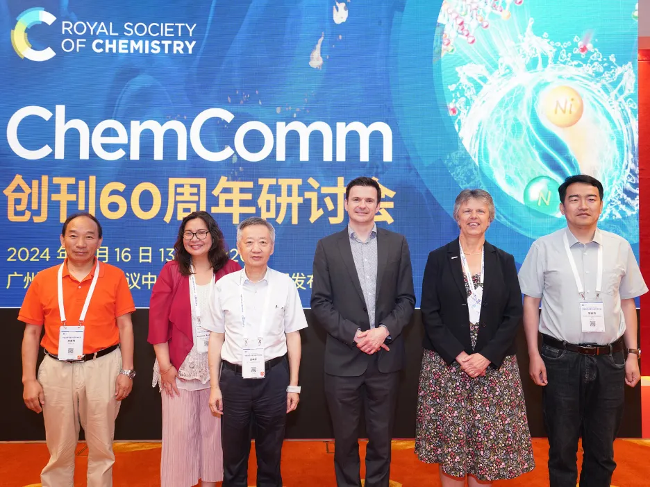 Professor Gill Reid (second right) joins five other people in front of a sign reading 'ChemComm' in English and "60th anniversary" underneath in Mandarin at an event in China