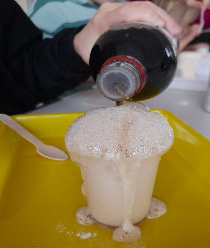 Coca-Cola is poured into a plastic cup, which is overflowing with foam