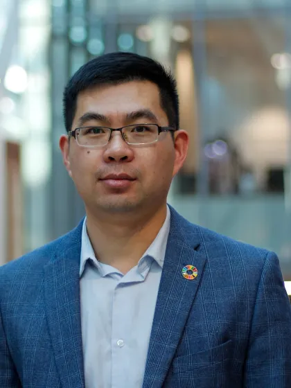 Dr Fanran Meng headshot, wearing glasses and a blue suit posing for camera