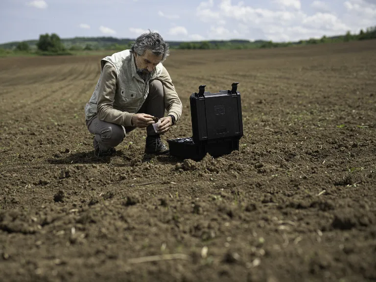 Scientist in a field taking soil sample to test soil quality