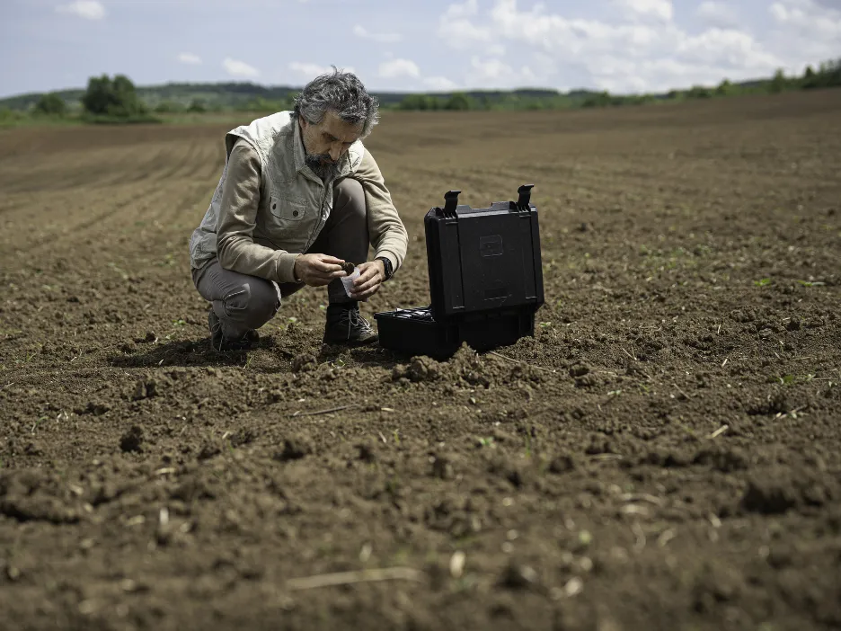 Scientist in a field taking soil sample to test soil quality