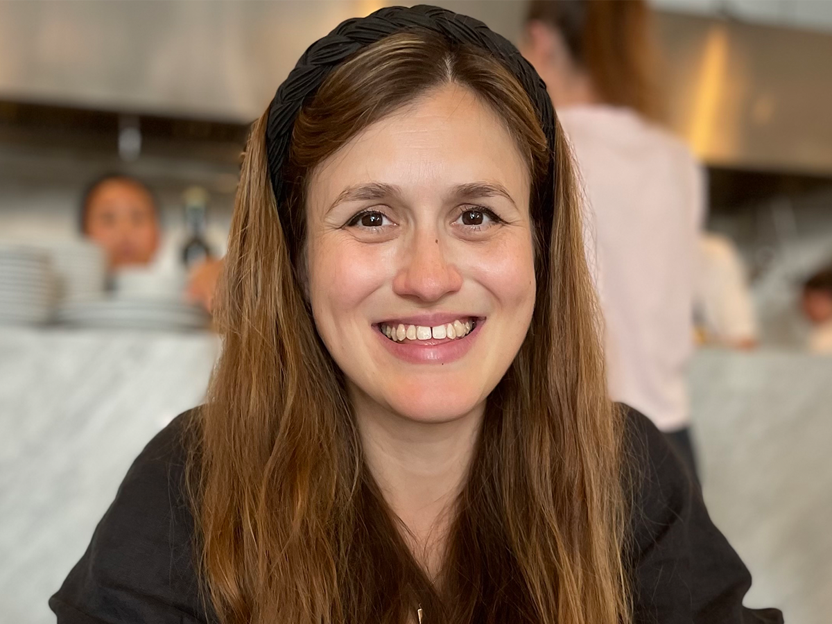 Dr Clare Bakewell with long brown hair smiling at camera
