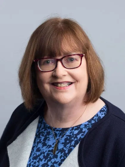 Professor Anita Maguire wearing glasses and a blue top, smiling for camera
