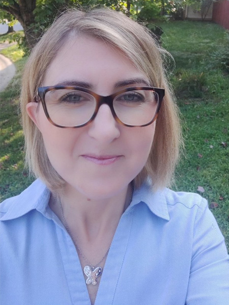 Marta Venier smiling for camera in blue shirt and glasses