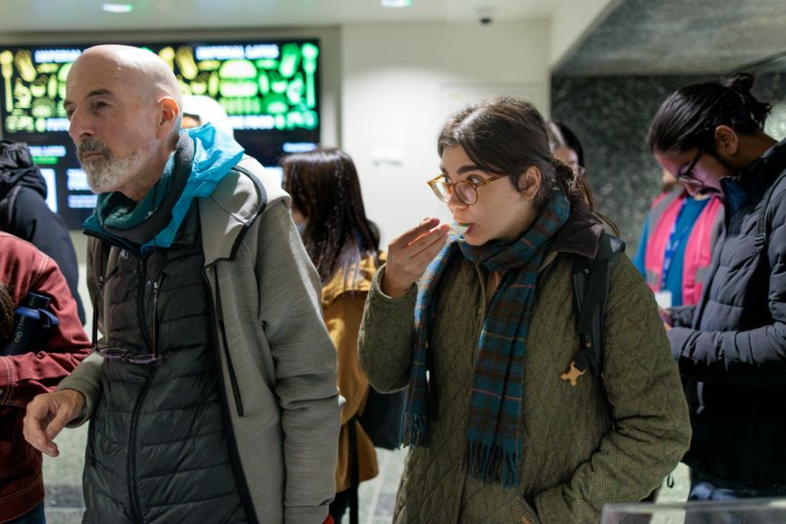 A woman eats a dessert off a plastic spoon.