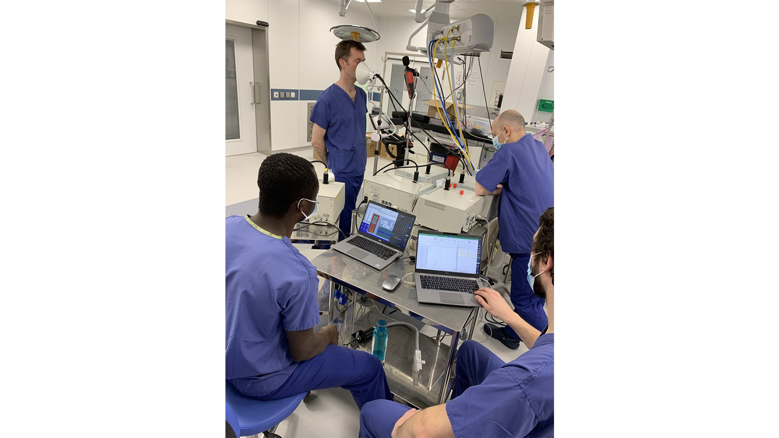 The PERFORM COVID-19 Team in scrubs sitting at a table with laptops while conducting experiments
