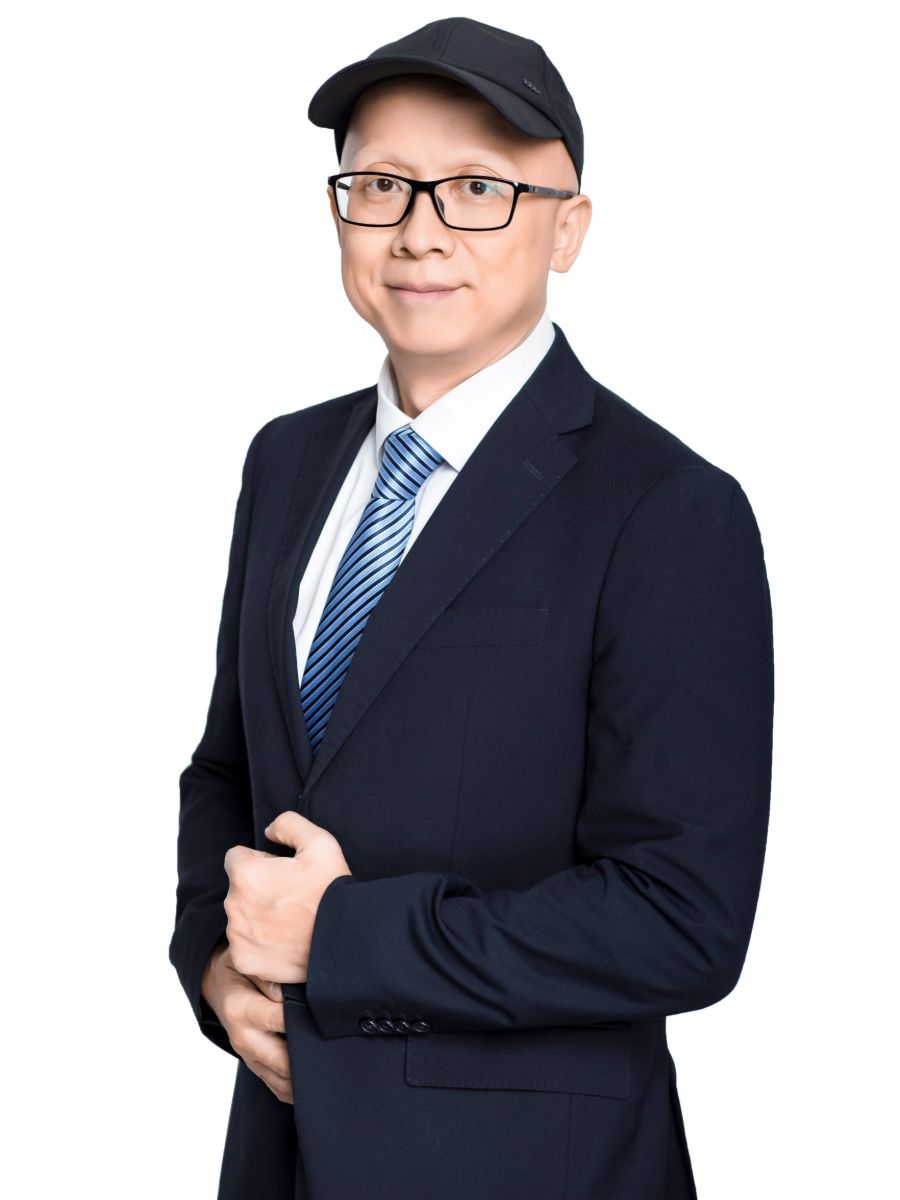 Professor Xingyu Jiang in a suite and tie and baseball cap smiling for camera