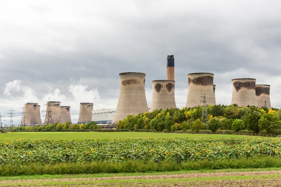 Drax, North Yorkshire, UK. October 4 2022. Drax Power in North Yorkshire with large cooling towers, chimney and electricity pylons, surrounded by forests, green fields and sunflowers. Horizontal.