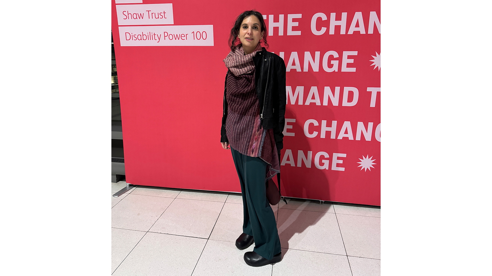 Professor Jennifer Leigh standing in front of a red sign saying "We demand change"