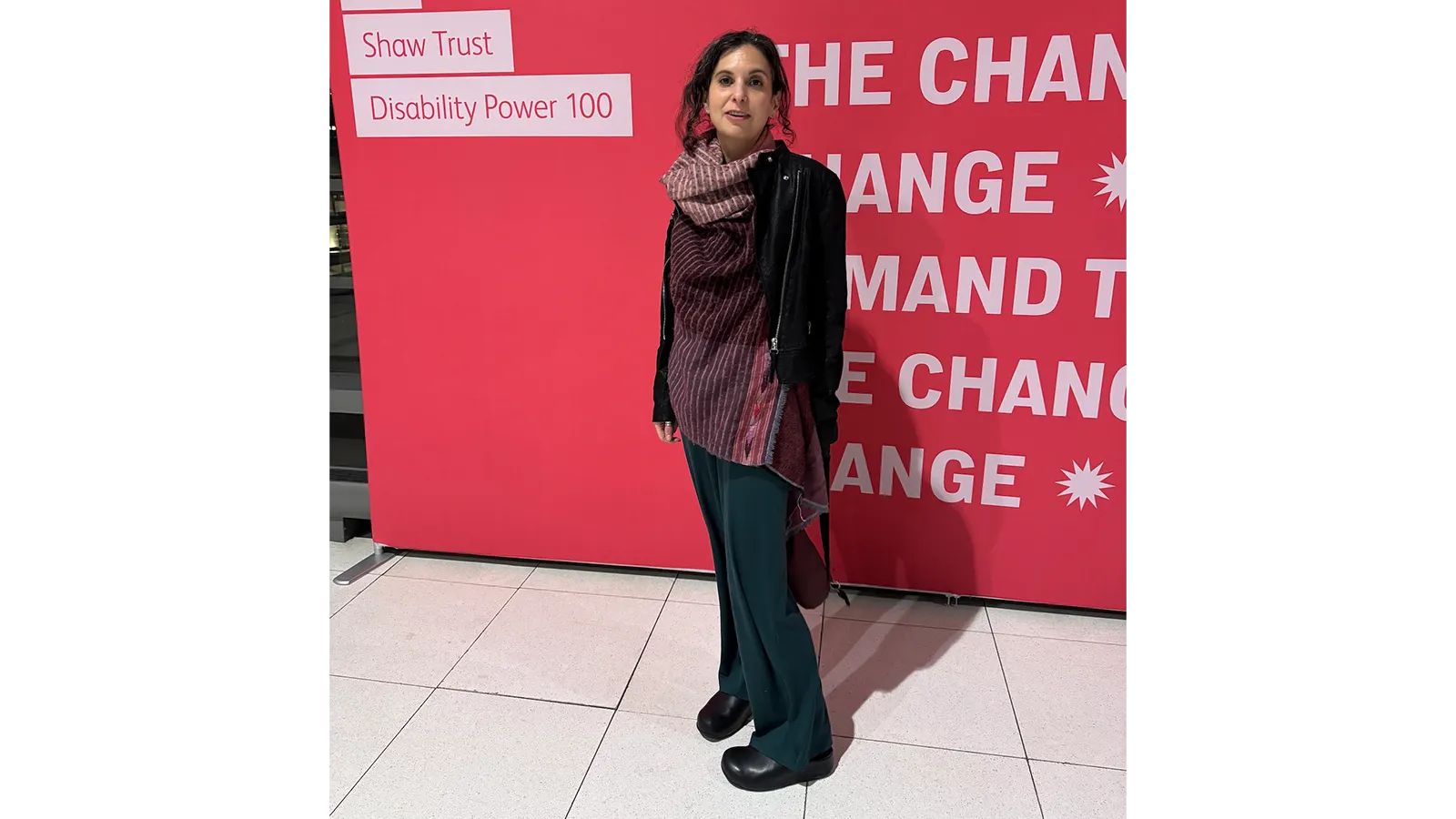 Professor Jennifer Leigh standing in front of a red sign saying "We demand change"