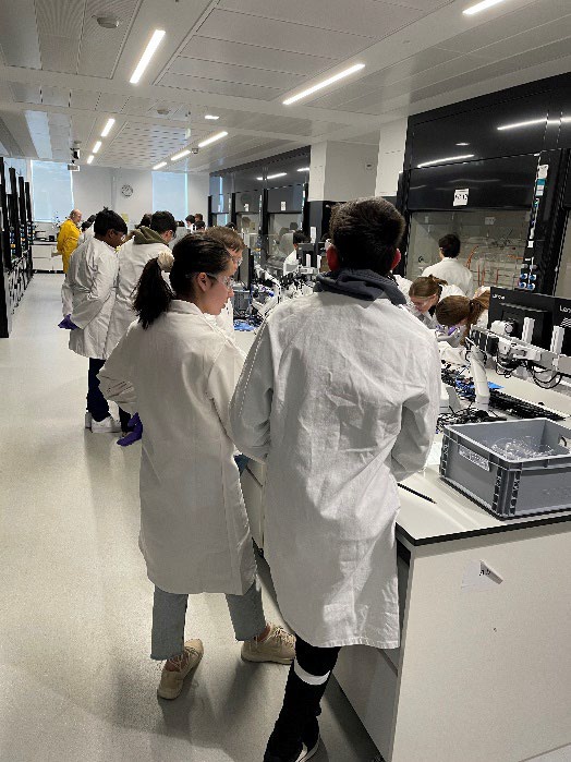 Students in white coats work in a laboratory