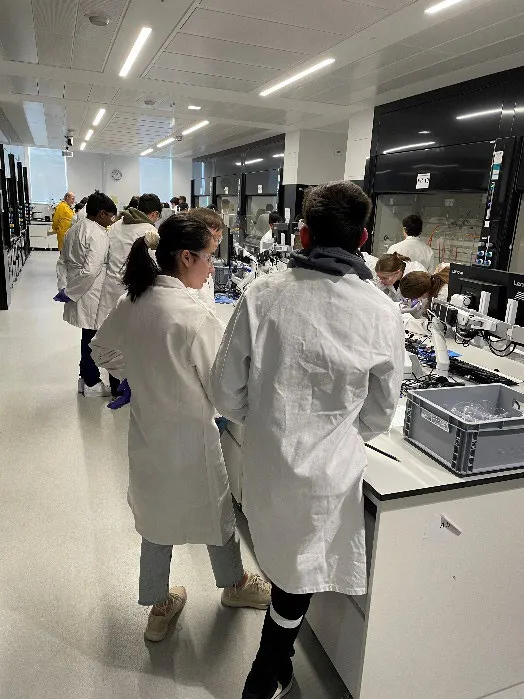 Students in white coats work in a laboratory