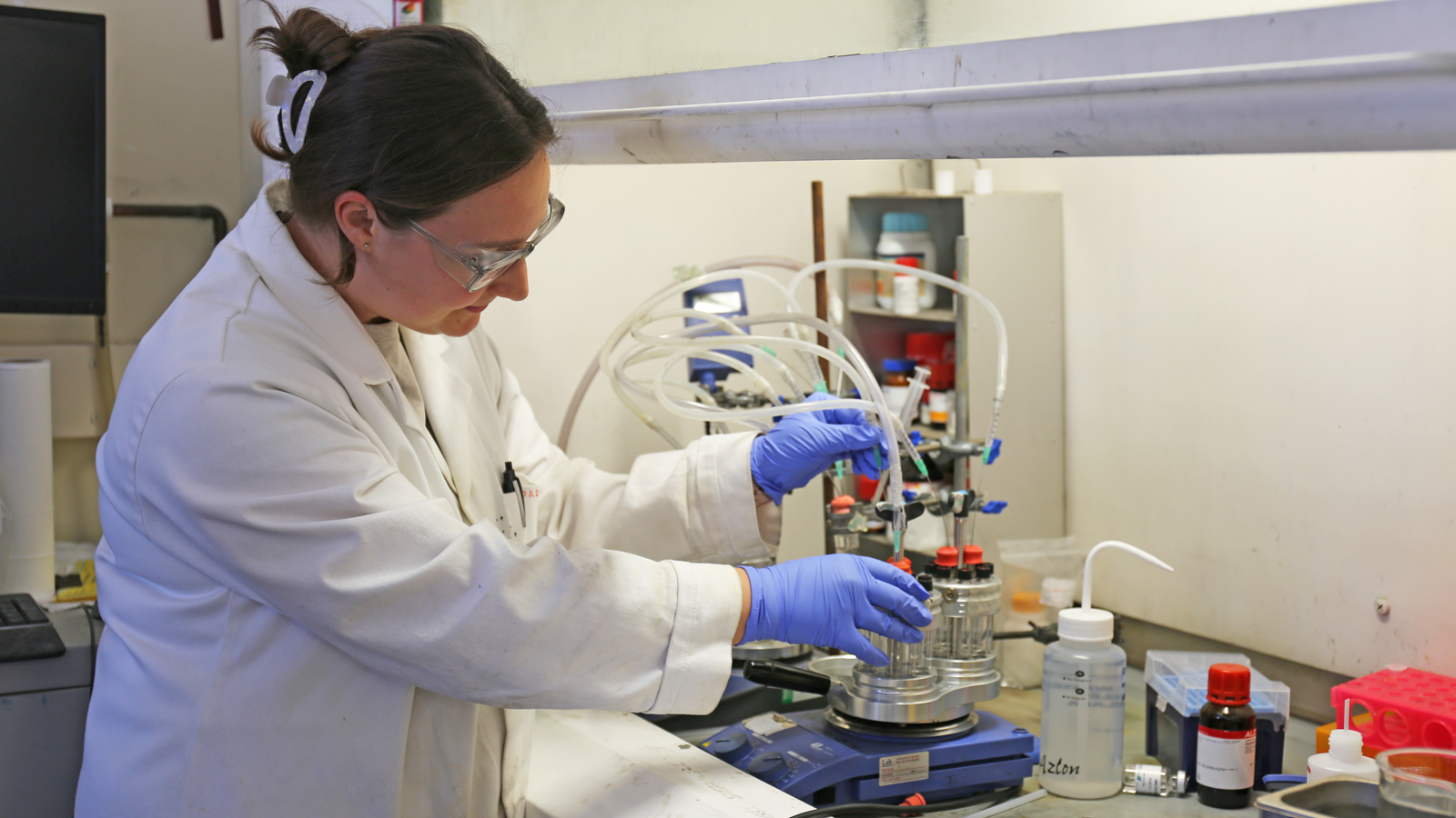 Biocatalytic Nitro Hydrogenations team member in a lab coat and gloves working with equipment in lab