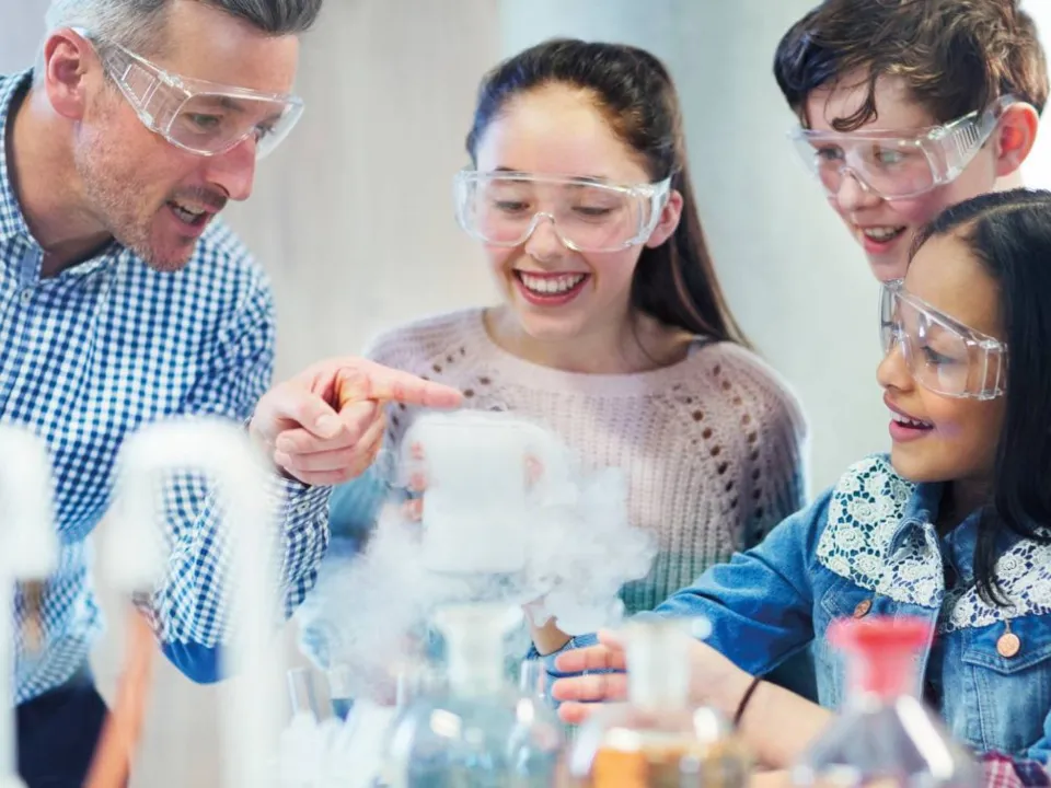Teacher with group of children smiling during practical demo