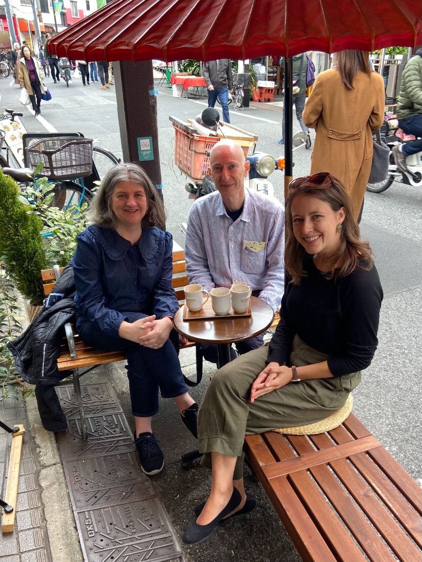 Helen Pain, Antony Galea and Sara Bosshart smile and sit together on a bench in Japan