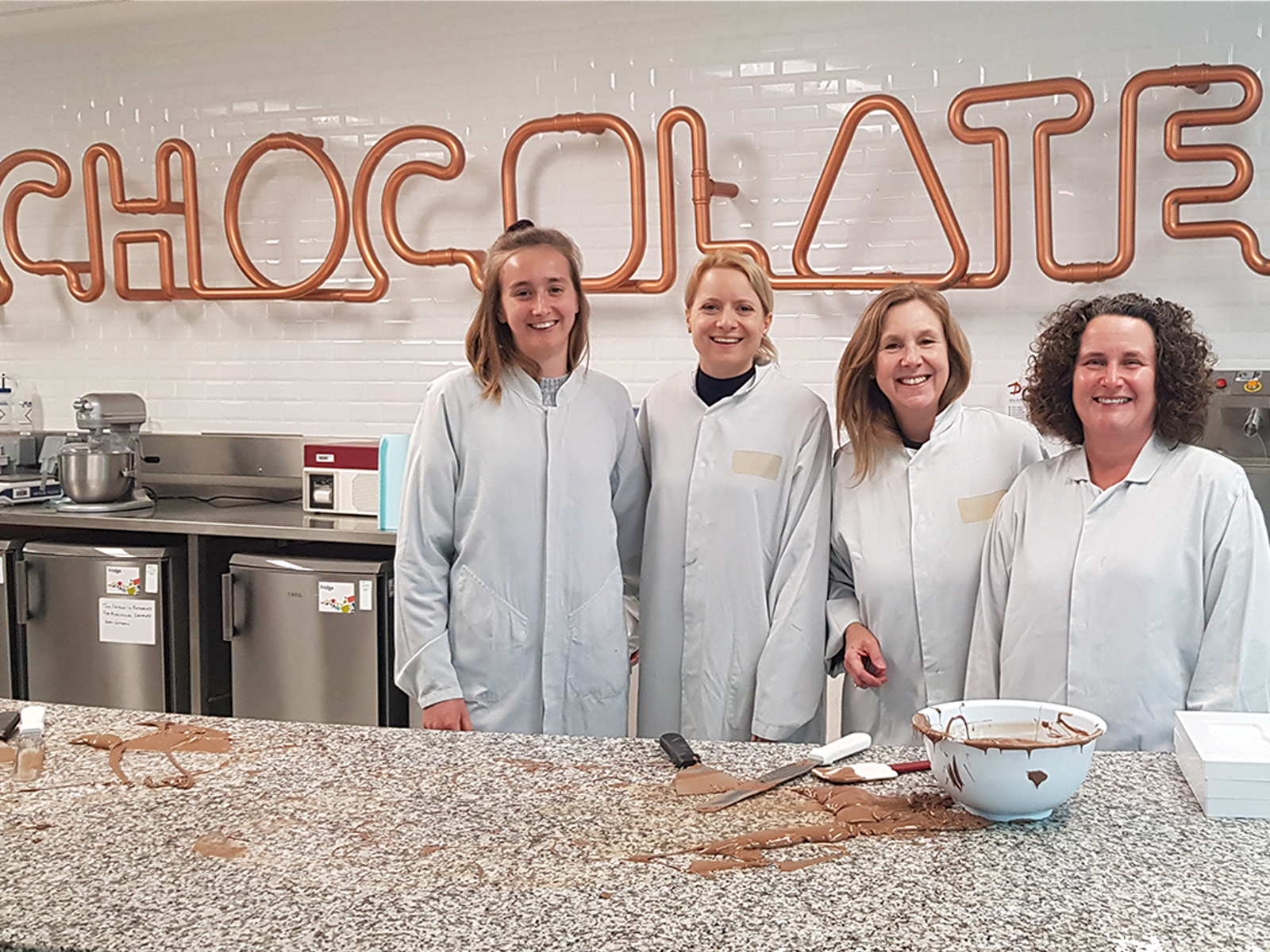 Image shows a group of people chocolate tempering with Kate Rose, apprentice food technologist at Mondelez, alongside Dr Stacey Lockyer, Elaine Hindal and Frances Meek from the British Nutrition Foundation. Image shows a group of people chocolate tempering with Kate Rose, apprentice food technologist at Mondelez, alongside Dr Stacey Lockyer, Elaine Hindal and Frances Meek from the British Nutrition Foundation.